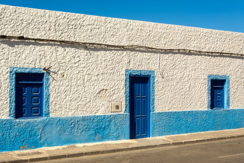 Blue and white painted house front under a clear sky.