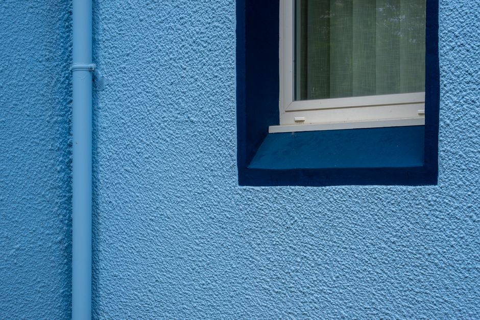 Blue painted wall with a window and a drainpipe.