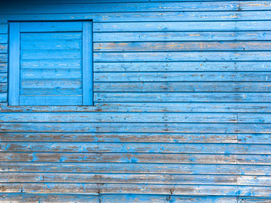 Weathered blue wood wall with peeling paint.